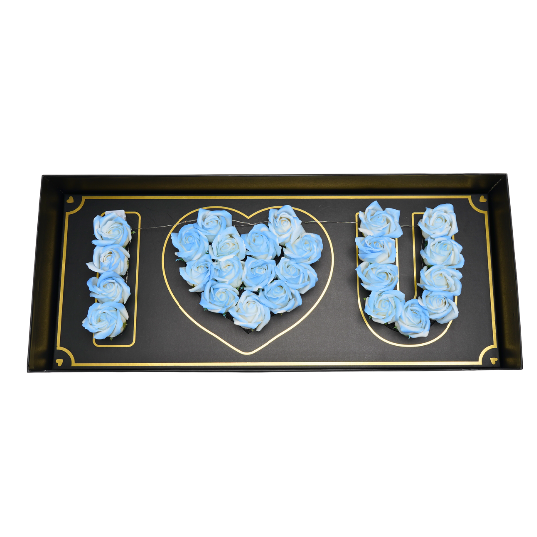 Black floral box with blue Eternal flowers that say I love you and has strings of small LED lights.