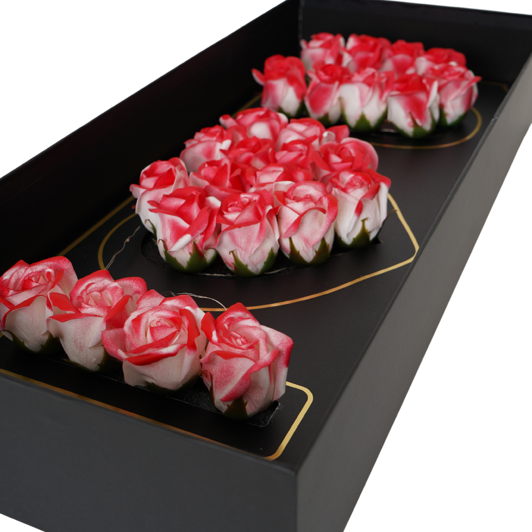 Black floral box with hybrid white/pink Eternal flowers that say I love you and has strings of small LED lights.