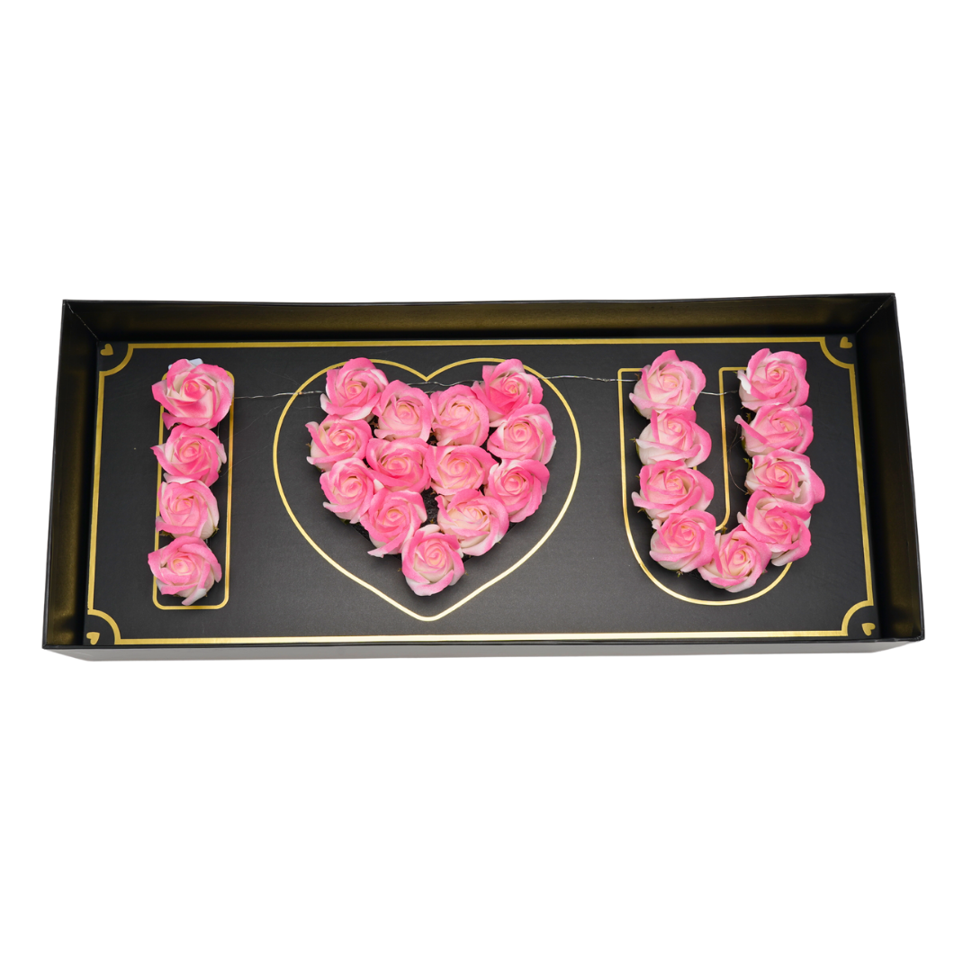 Black floral box with pink green Eternal flowers that say I love you and has strings of small LED lights.