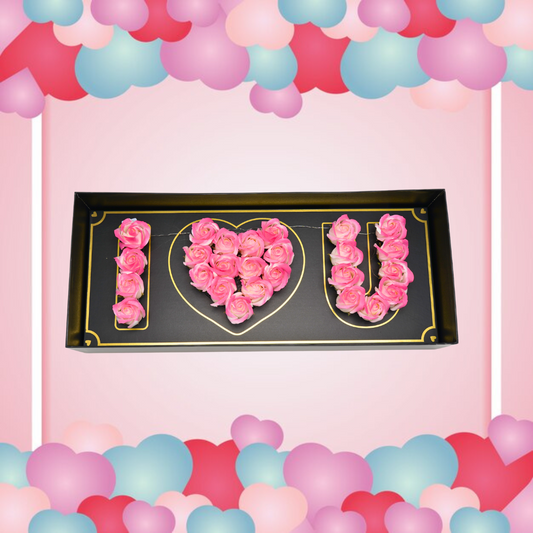 Black floral box with pink green Eternal flowers that say I love you and has strings of small LED lights.